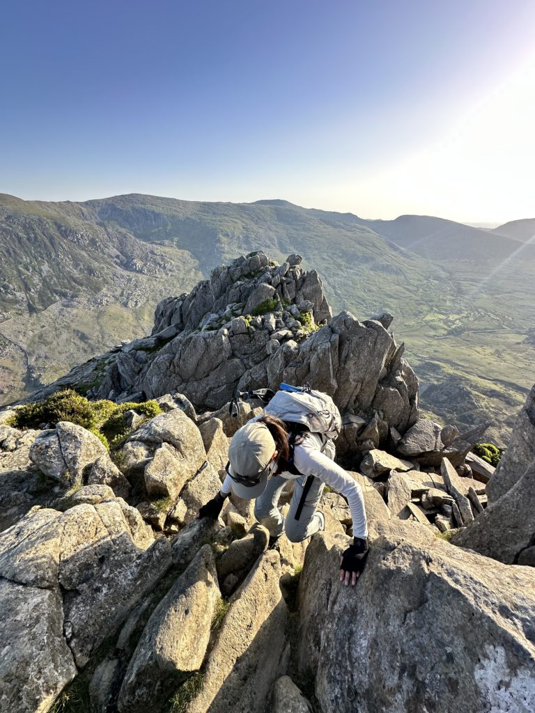 woman hiker scrambling along the rocky Tryfan North Ridge in Snowdonia