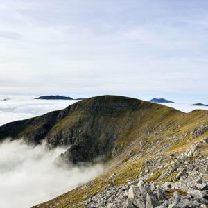 Cloud inversion over Eryri seen from the summit of Pen yr Ole Wen with mountains rising above a sea of clouds